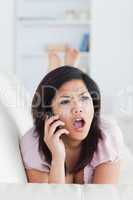 Chocked woman phoning while resting on a couch