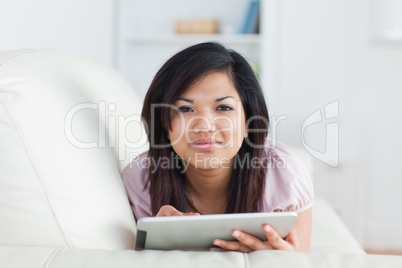 Woman typing on a tablet while resting on a couch