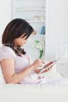 Woman holding a tablet while she sits on a sofa