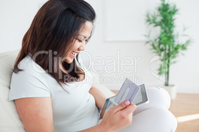 Woman on a couch while holding a tactile tablet and a card