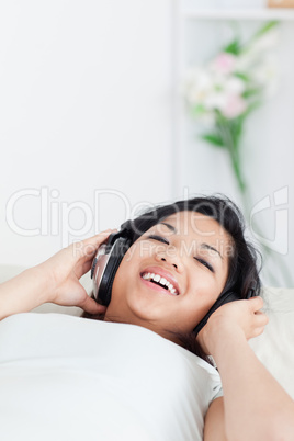 Smiling woman lying on a sofa with headphones on