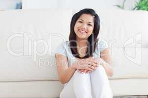 Woman smiles as she sits on the floor in a living room
