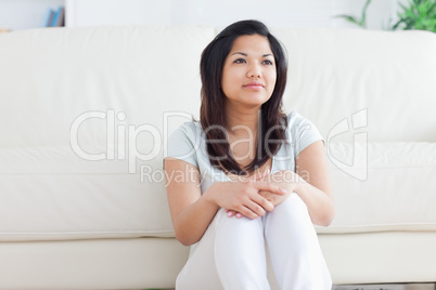 Woman smiling as she sits on the floor in front of a couch