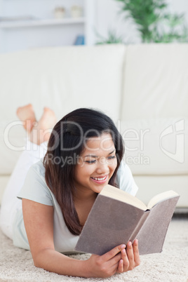 Woman lays on the floor as she reads a book