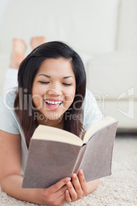 Smiling woman reading a book as she sits on the floor