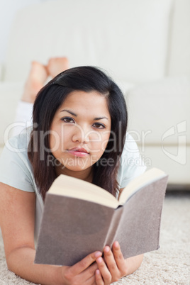 Woman holding a book while lying on the floor