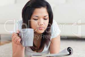 Woman holding a mug while reading a magazine