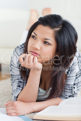 Woman holding her head with her fist on the floor with a book an