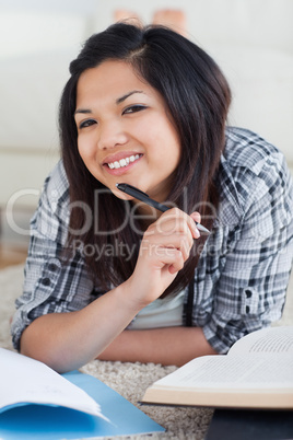 Smiling woman holding a pen as she lays on the floor