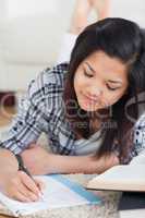 Woman lying on the floor while writing on a notebook