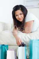 Woman lying on a sofa while taking off clothes from a shopping b