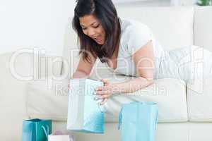 Surprised woman on a couch looking in a shopping bag