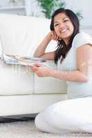 Smiling woman on her knees while holding a magazine