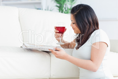 Woman on her knees reading a magazine and holding a glass of red