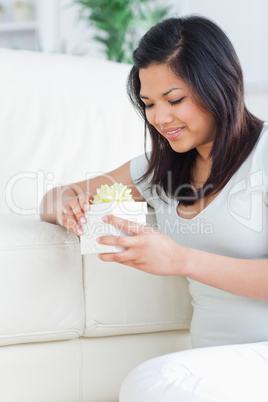 Woman holding up a gift as she stands on her knees in front of a