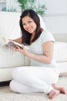 Woman holding a book while sitting in front of a couch