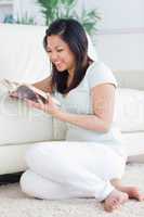 Woman reading a book while sitting on a  white couch