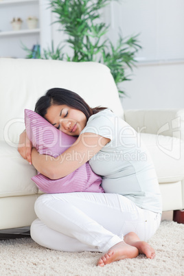 Sleeping woman holding a pillow while sitting on the floor