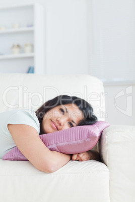 Woman resting her head on a pillow while lying on a couch