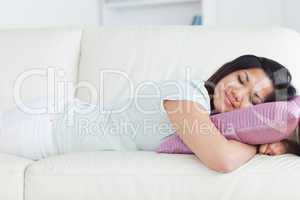 Woman sleeping on a white sofa and holding a pillow