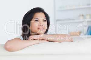 Thinking woman crossing her arms as she stands on a white couch