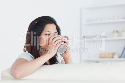 Woman drinking from a mug while holding it with two hands