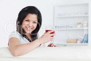 Woman holding a glass of red wine with one hand while resting he