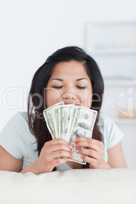 Woman closing her eyes as she holds some dollar bills