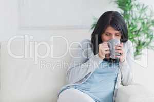 Woman drinking a mug while relaxing on a sofa