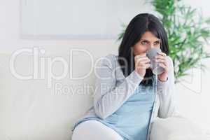 Woman drinking from a mug and holding it with two hands