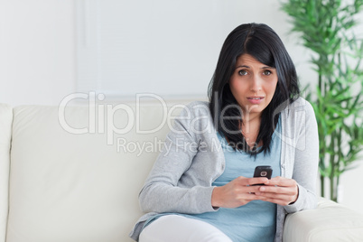 Woman holding a phone while sitting on a couch