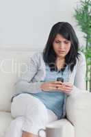 Woman using a phone while relaxing on a sofa