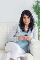 Woman holding a phone while relaxing on a couch