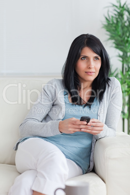 Woman holding a phone while crossing her legs and relaxing on a