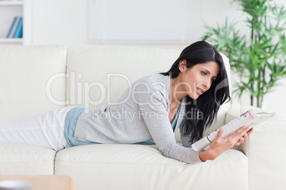 Woman reading a magazine while resting on a couch