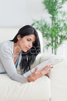 Woman reading a magazine while relaxing on a couch