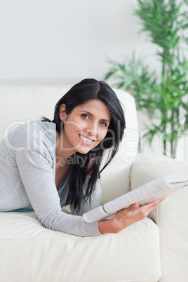 Woman holding a magazine as she lies on a sofa