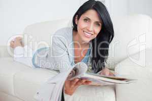 Woman holding a magazine while laying on a couch