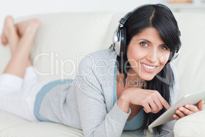 Smiling woman with headphones on while holding a tablet