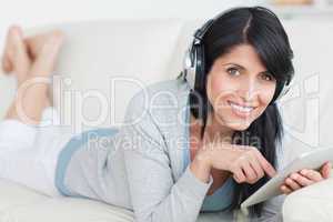 Smiling woman with headphones on while holding a tablet