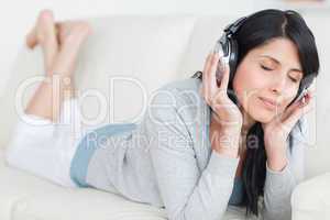 Woman laying on a sofa while wearing headphones