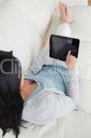 Woman lying on a sofa while touching a tactile tablet