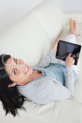 Woman relaxing on a sofa while touching a tablet