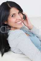 Woman smiling while holding a phone next to her ear