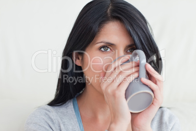 Woman drinking from a mug that she holds with two hands