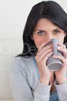 Close-up of a woman drinking from a mug that she holds with two