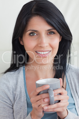 Close-up of a woman smiling while holding a mug