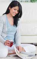 Woman with a glass of red wine in her hand while she turns pages