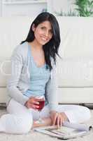 Woman sitting on the floor while holding a glass of red wine and