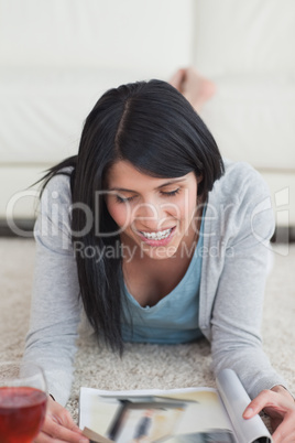 Woman smiling while lying on the floor and reading a magazine